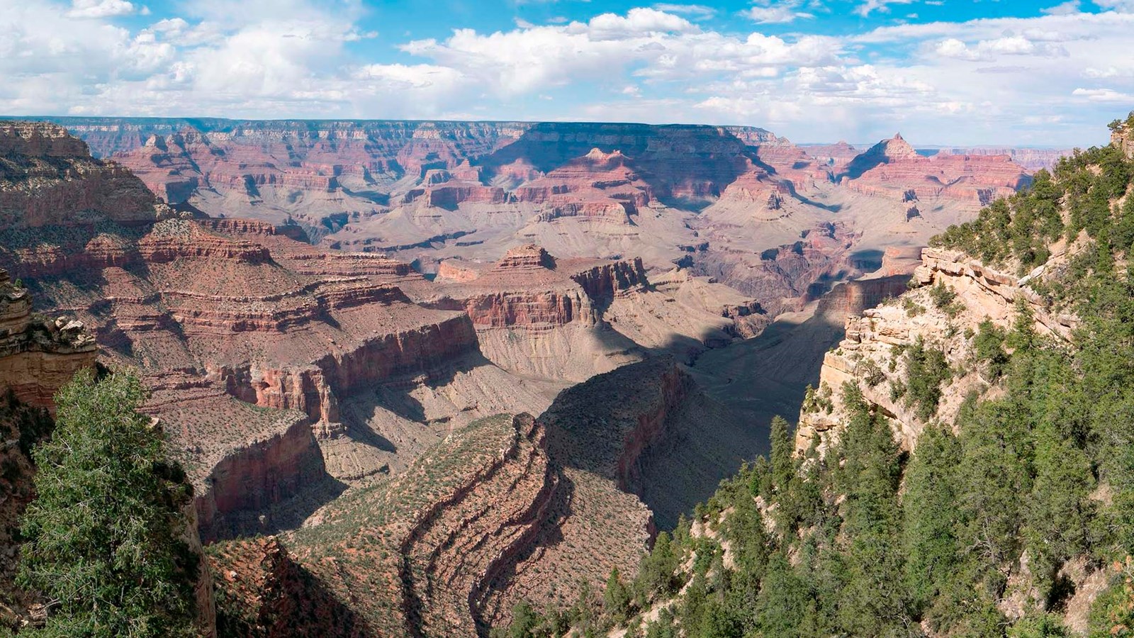 Afternoon view down into a mile deep canyon filled with colorful peaks and cliffs. 