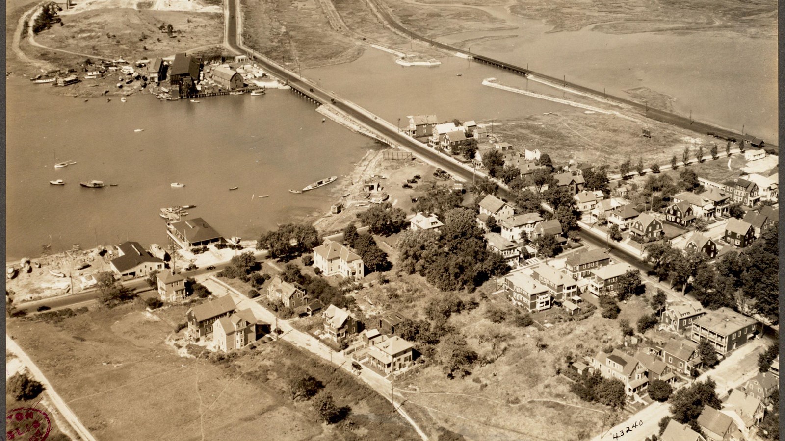 Aerial view of coastal land with houses with two bridges leading to another island with houses.