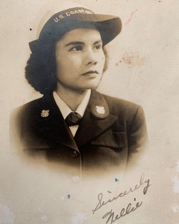 Sepia photo of a young woman in a military uniform and a cap, with cursive "Sincerely, Nellie."