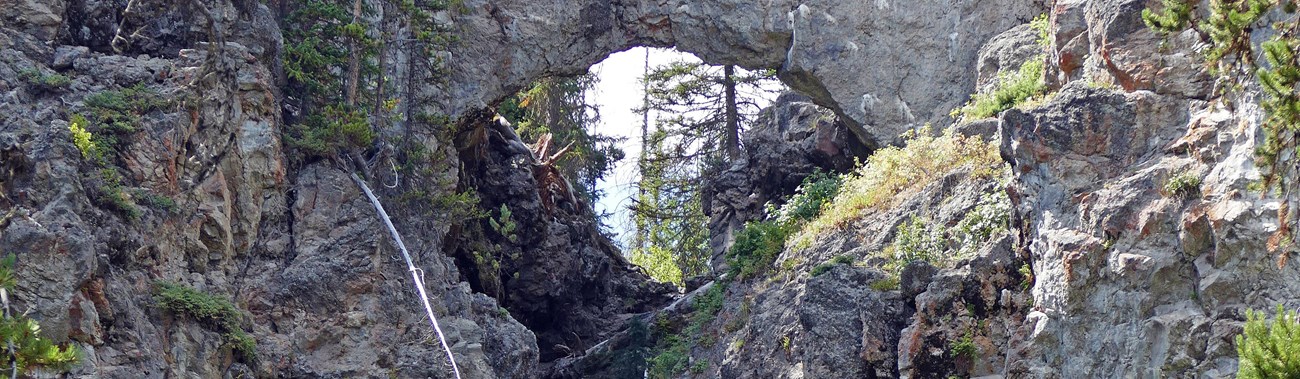 Gray stone rock arches over a creek drainage.
