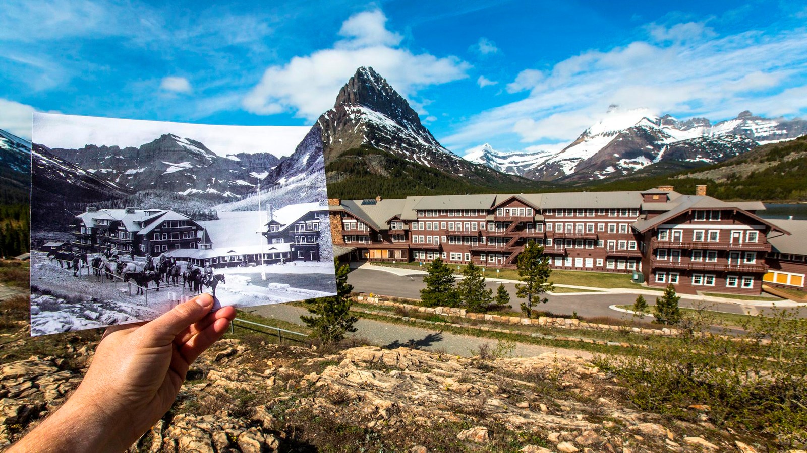 A rustic brown-wooden hotel sits in front of a mountain range. A black and white image aligns.