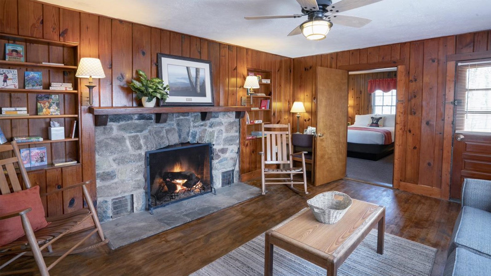 The interior of a lodge with wood walls and a stone fireplace.