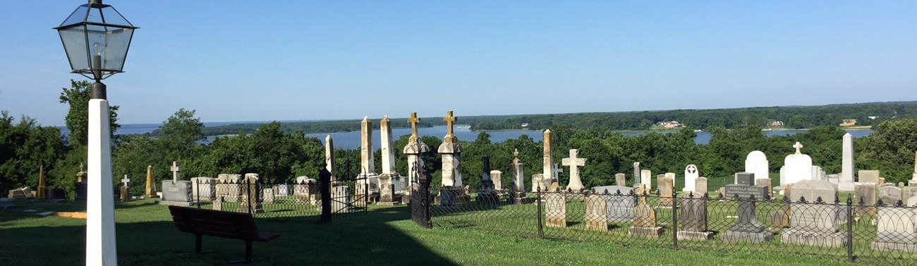 view from a bluff with a cemetery in the foreground and with a creek and forest in the distance 