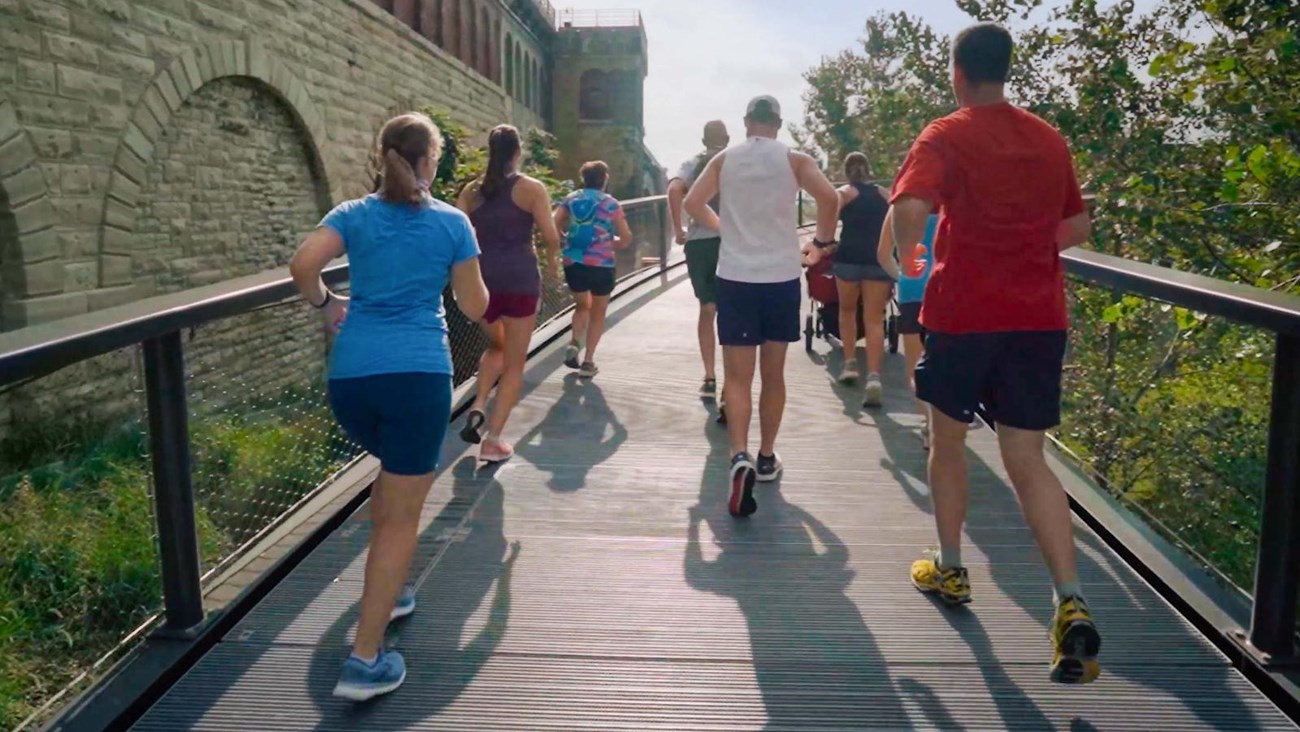 a group of men and women running or jogging along a path