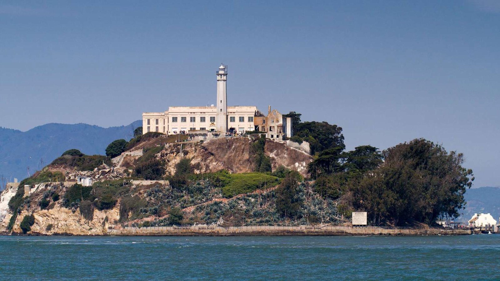 The lighthouse and prison can be seen on Alcatraz island from the water.