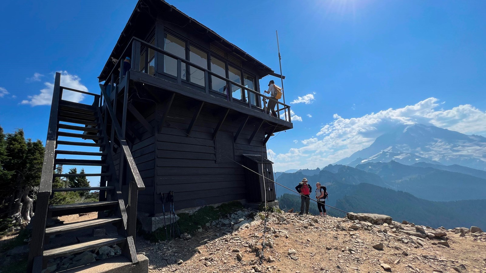 Two-story wooden fire lookout with view of glaciated mountain