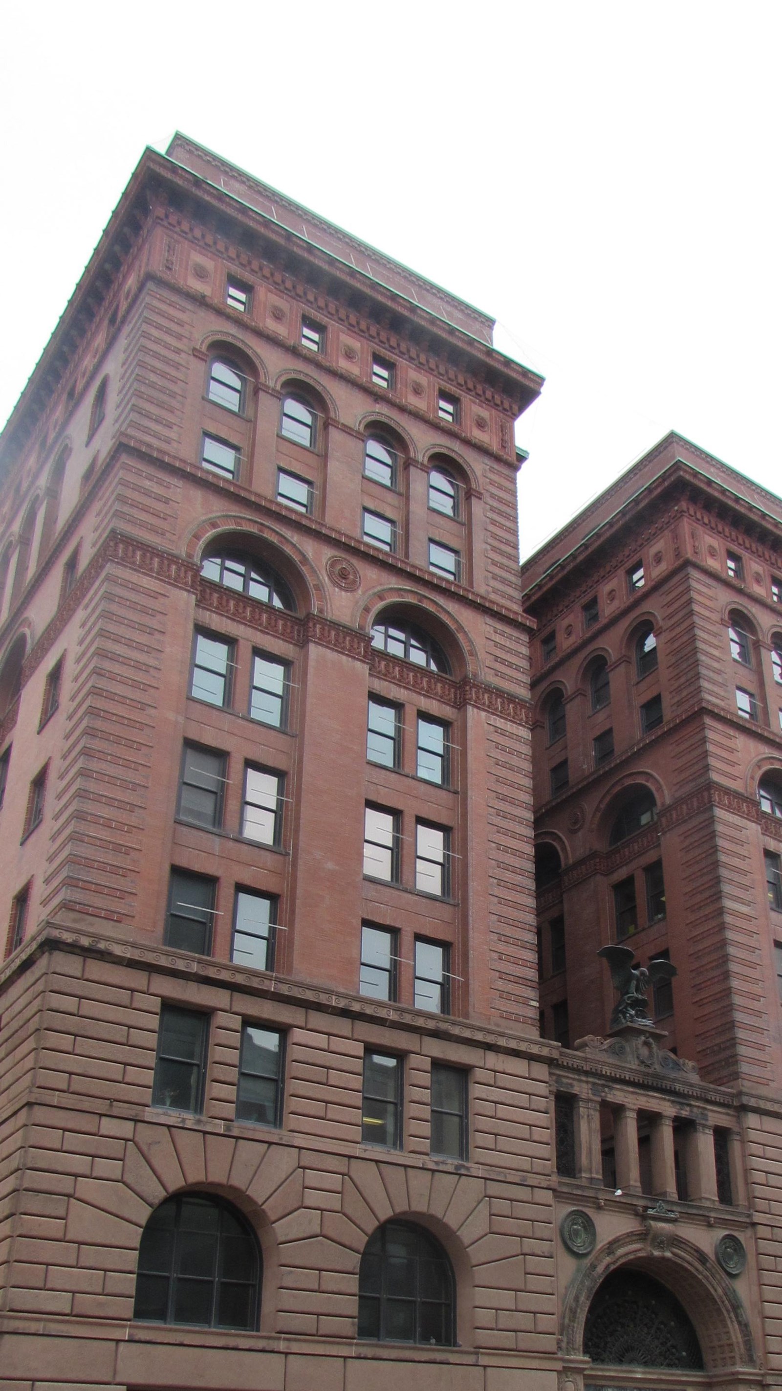 Large, brick H-shaped building with recessed middle entry, Eight stories tall.