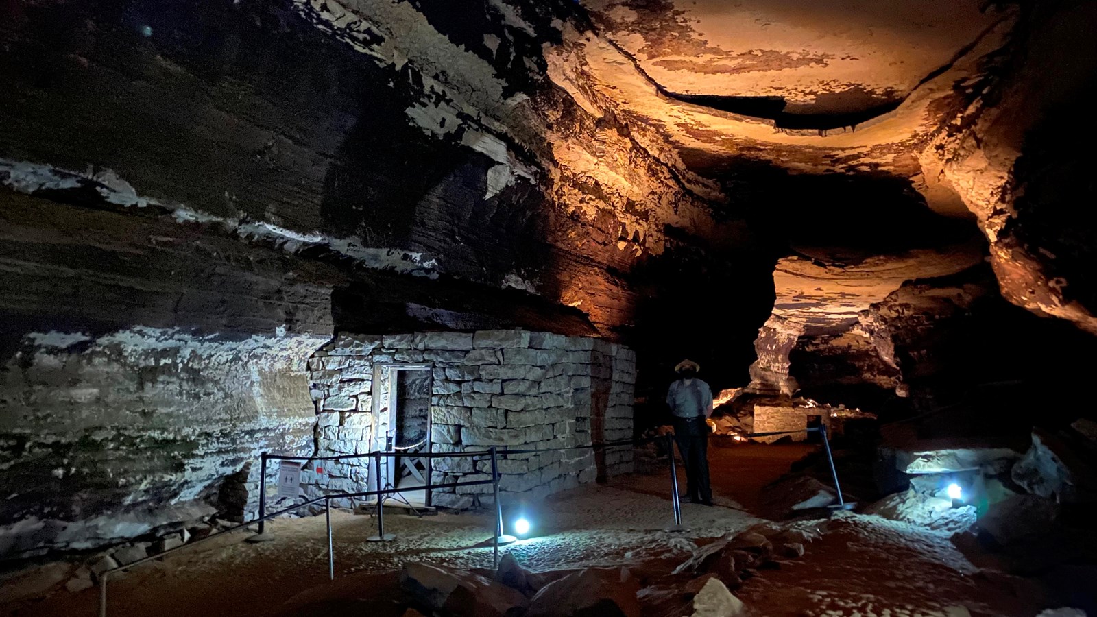 A stone building is lit up inside the cave. 