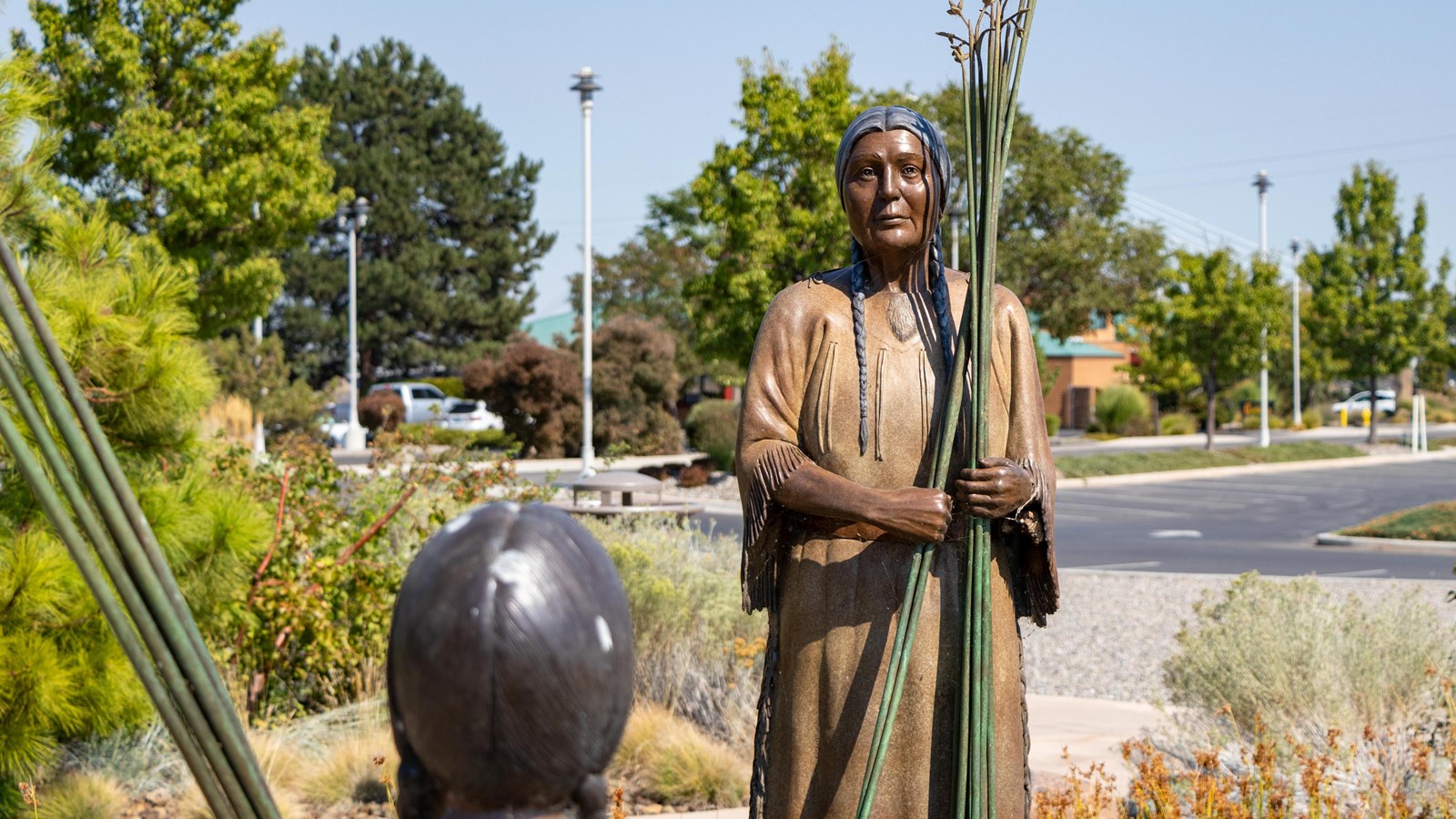 Color photograph of two hyper-realistic sculptures of Native Americans looking at each other. 