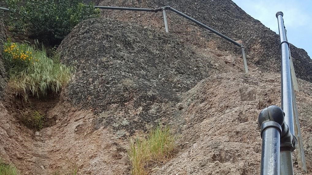 Handrail and series of foot notches carved into steep rock.