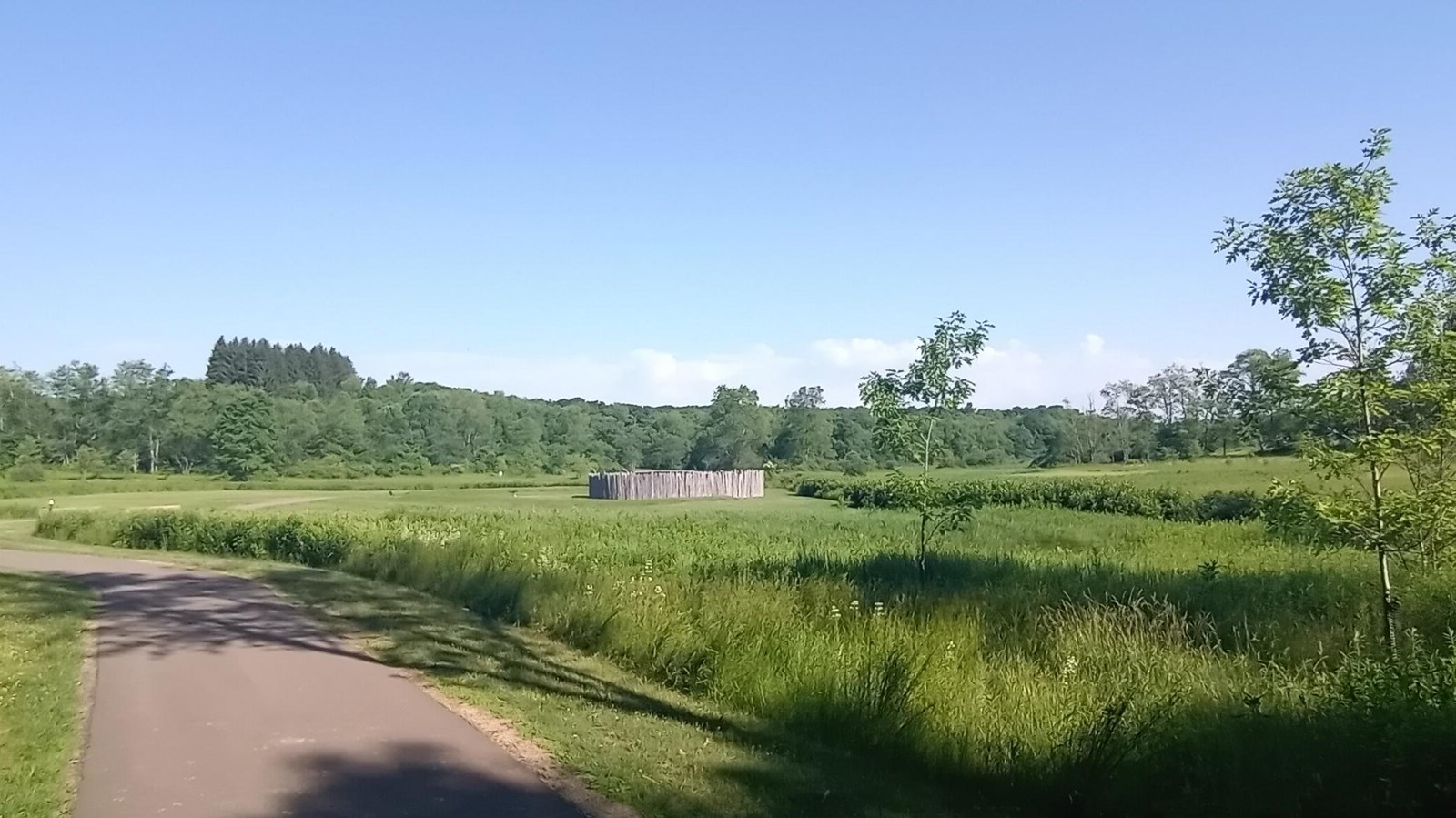 A view of a wide open grassland with the stockade of Fort Necessity in the center.