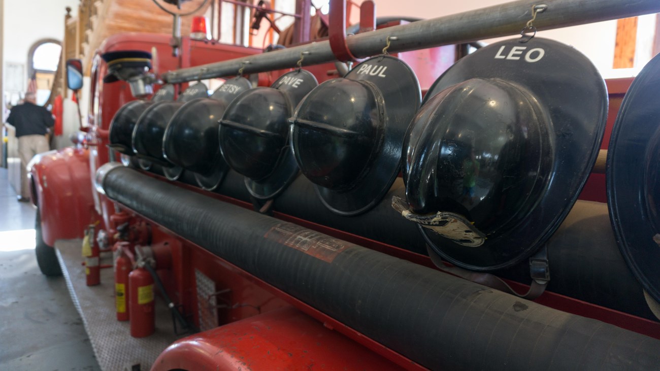 a historic fire truck with helmets mounted on the side