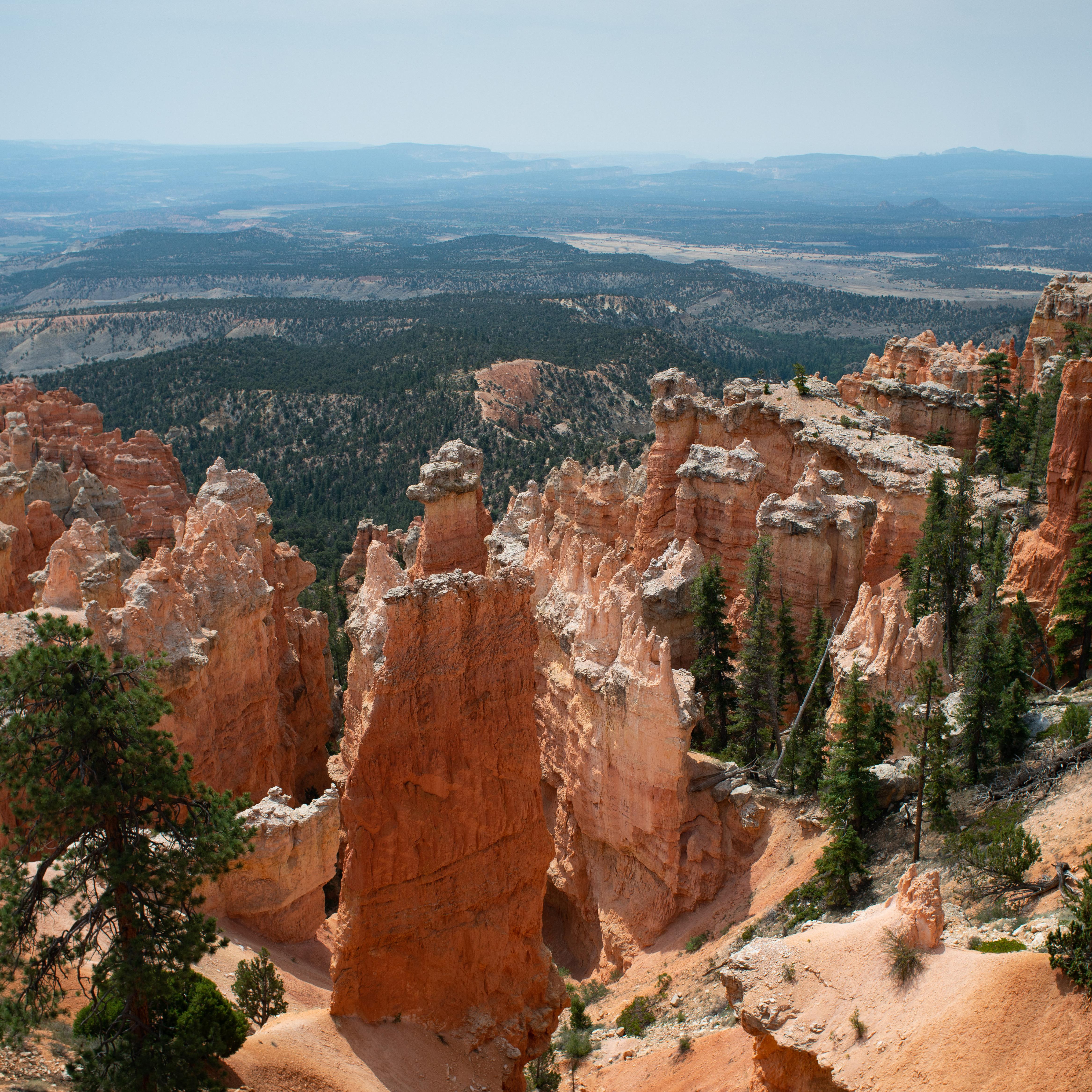 A landscape of red rocks in the foreground with hazy mountains on the horizon