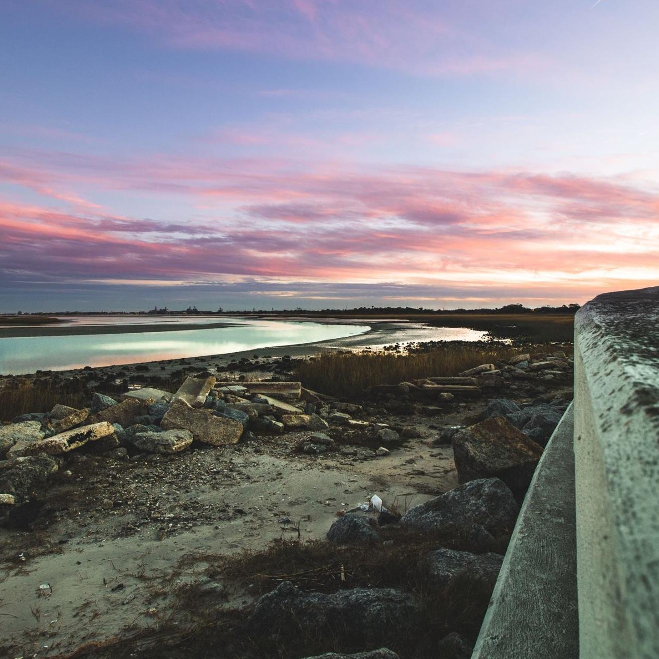 pink and purple sunrise next to seawall and river