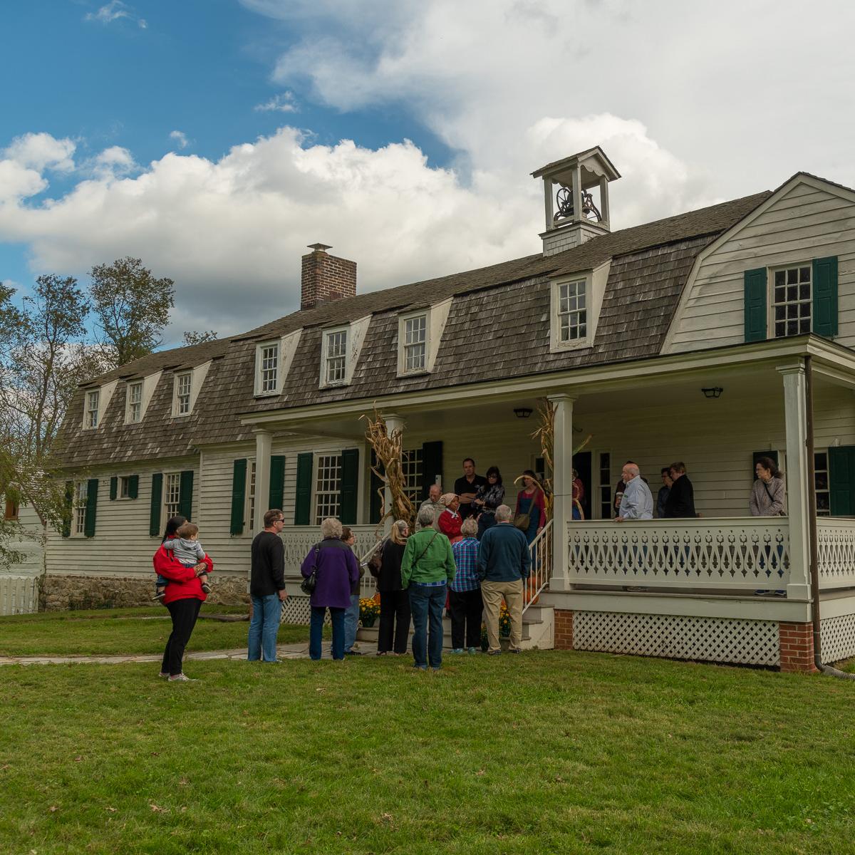 A group of people gather on the front steps of the lower farm house.