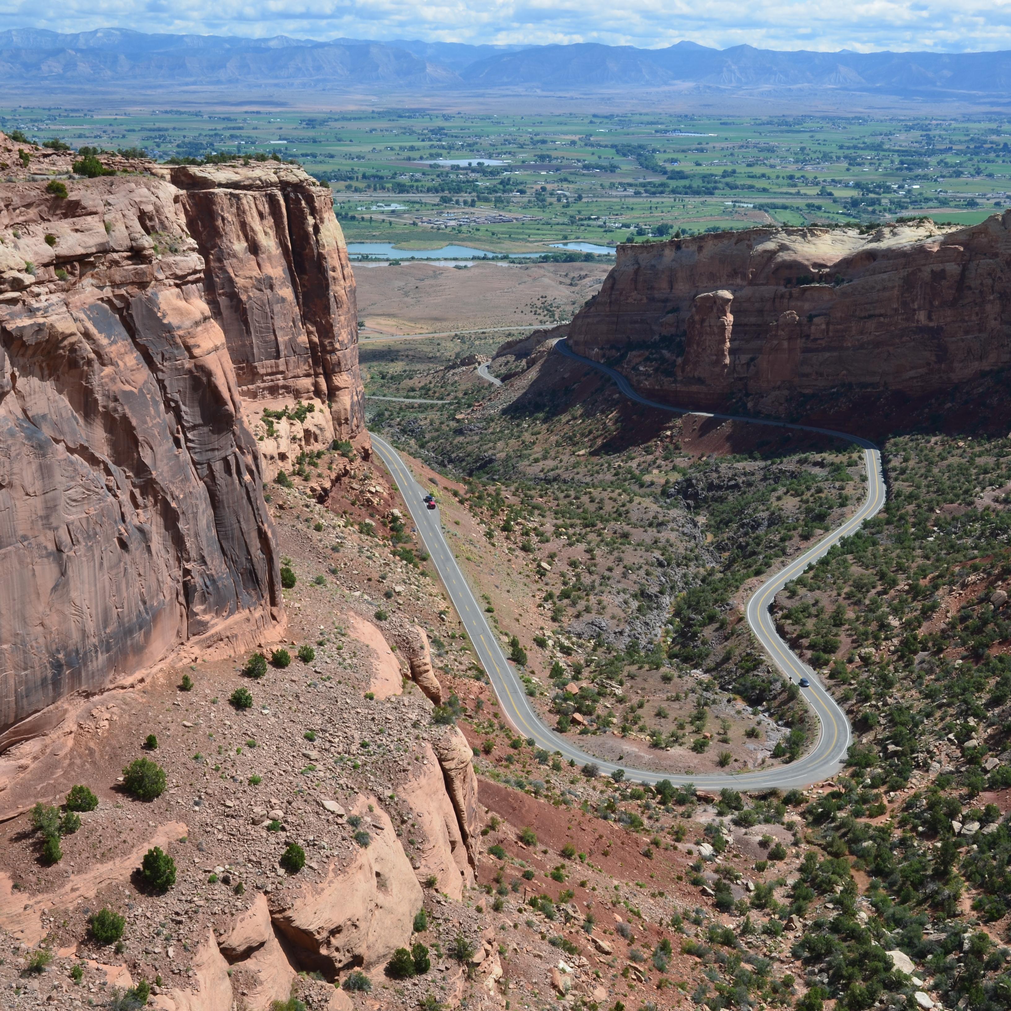 Looking down at road as it curls into and out of red rock canyon.