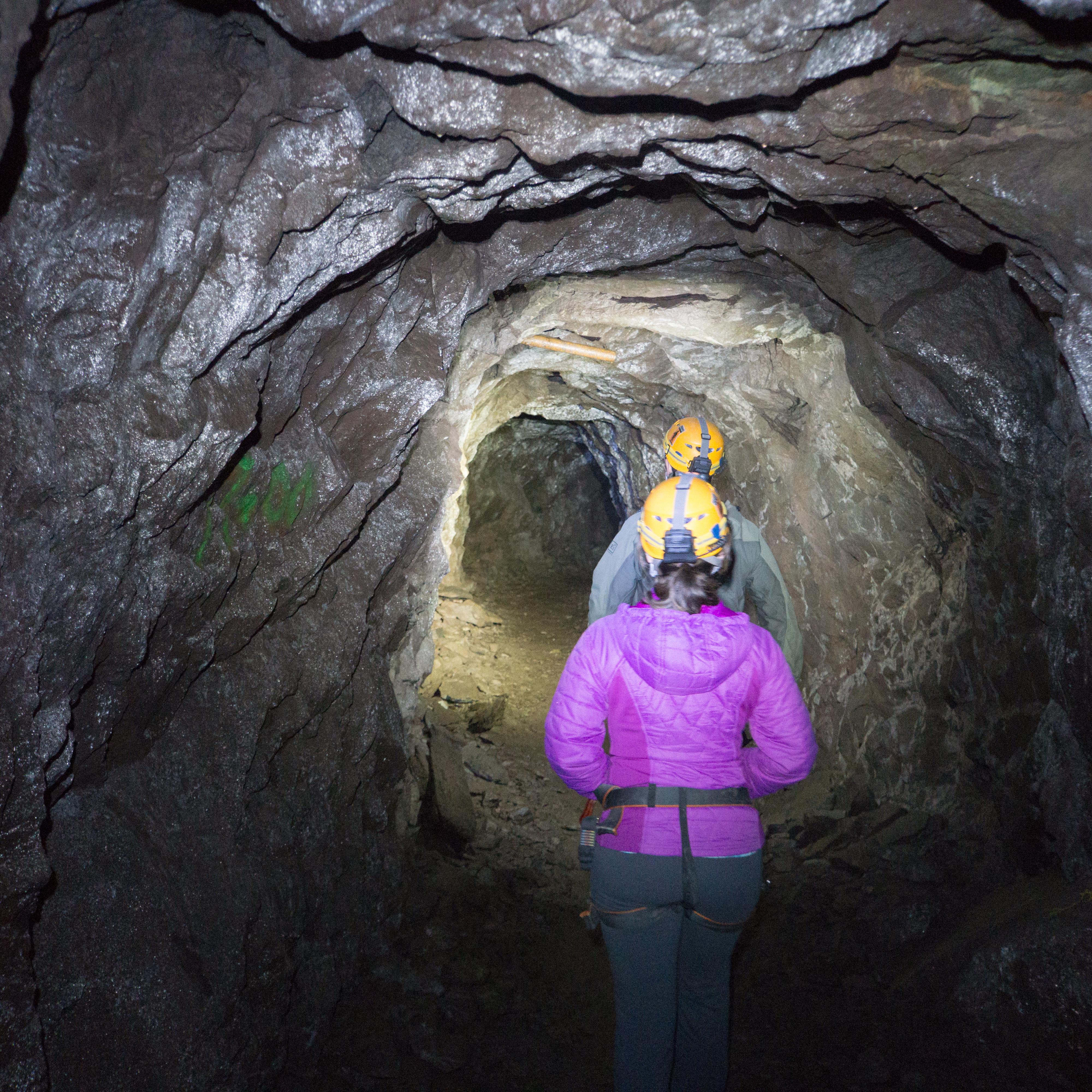 Two people walking underground in a small tunnel 