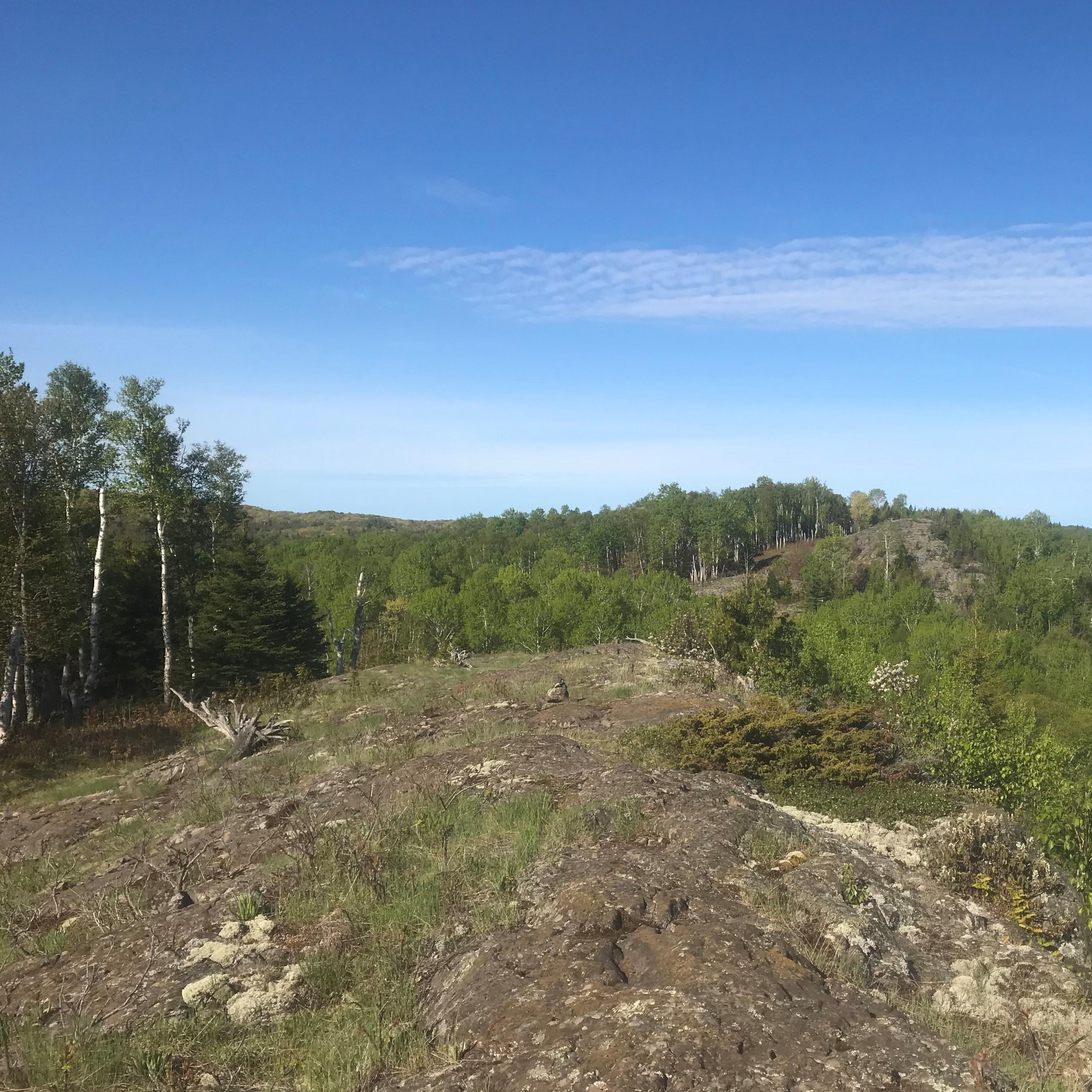 The trail crosses an exposed rocky ridge surrounded by forest. 