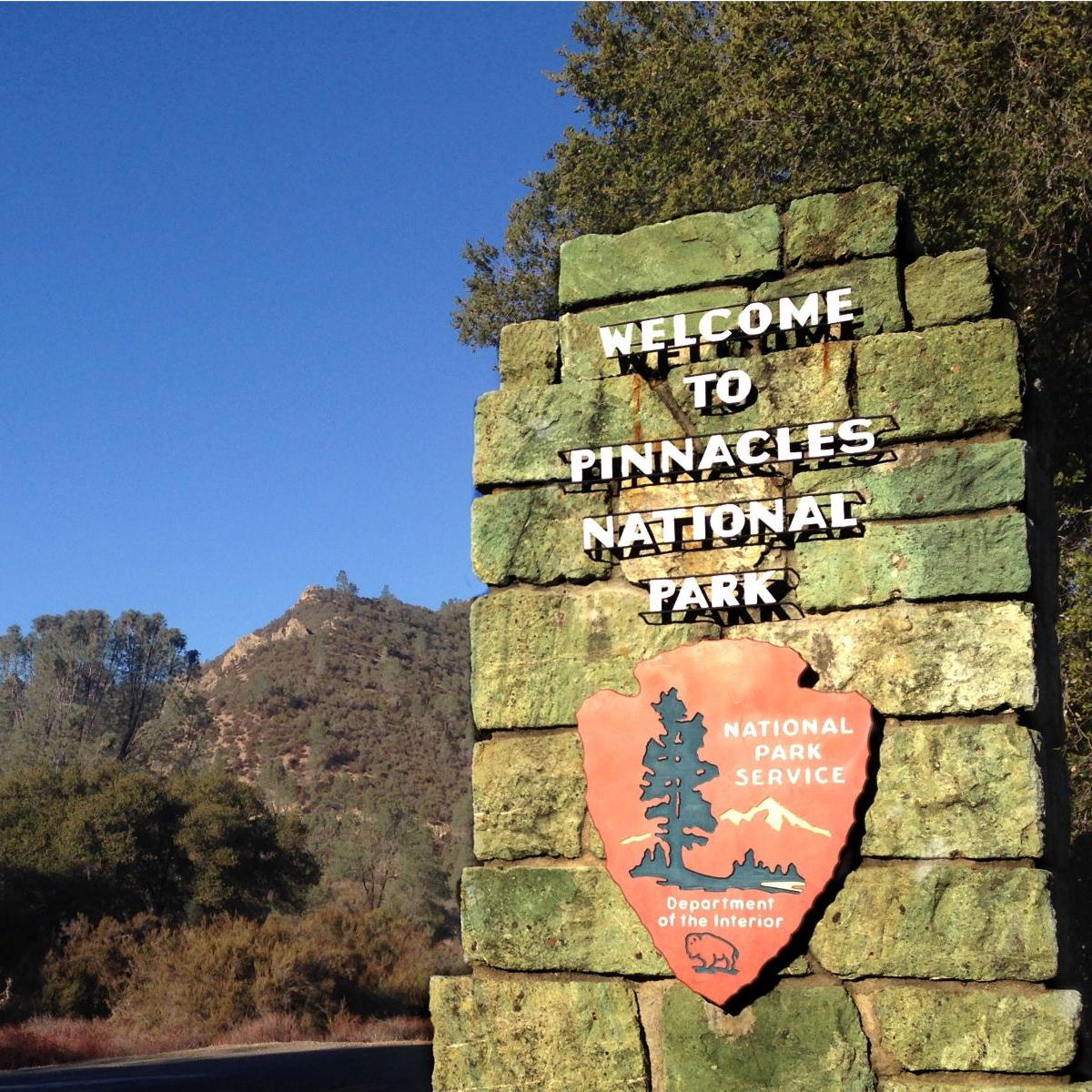 Rock pillar that reads Welcome to Pinnacles National Park with rock formations in distance