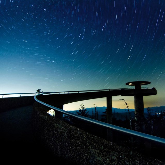Sloping walkway leading to observation tower against starry night sky