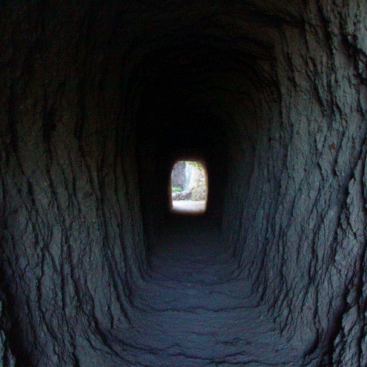 Natural light luminating the walls inside a manmade rock tunnel 