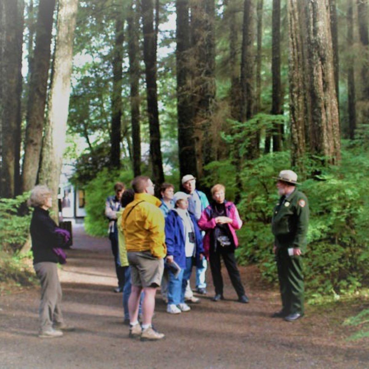 A park ranger speaking with visitors on a forest trail