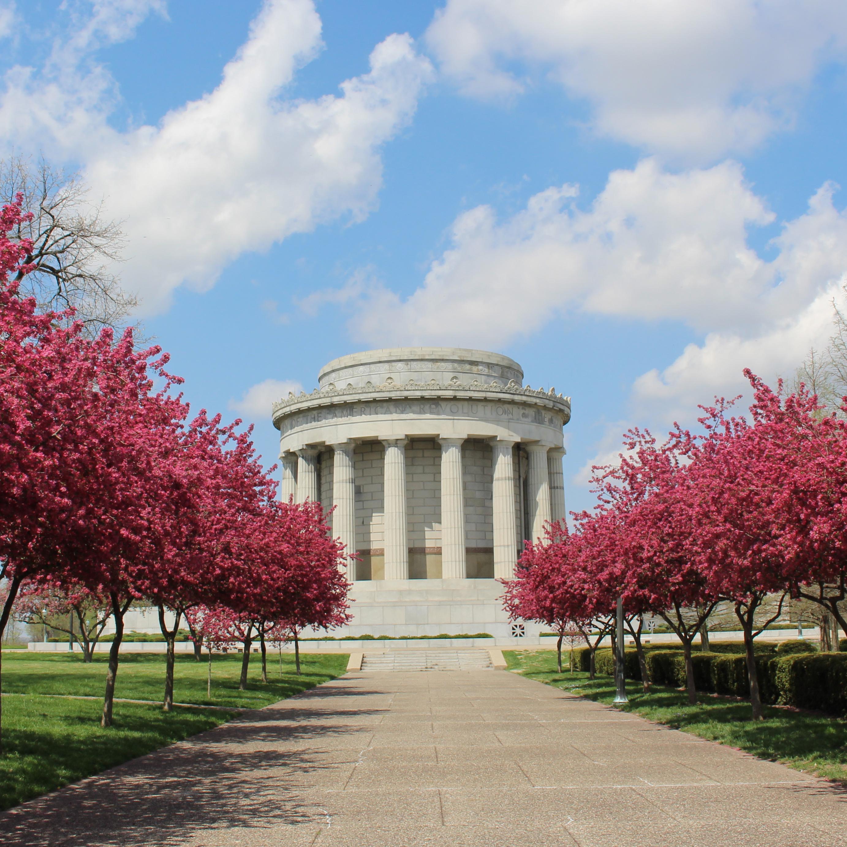 Sidewalk lined by crabapple trees flowering pink leading to the Clark Memorial