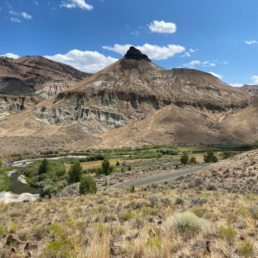A tall pointed formation with fields and a road in front of it