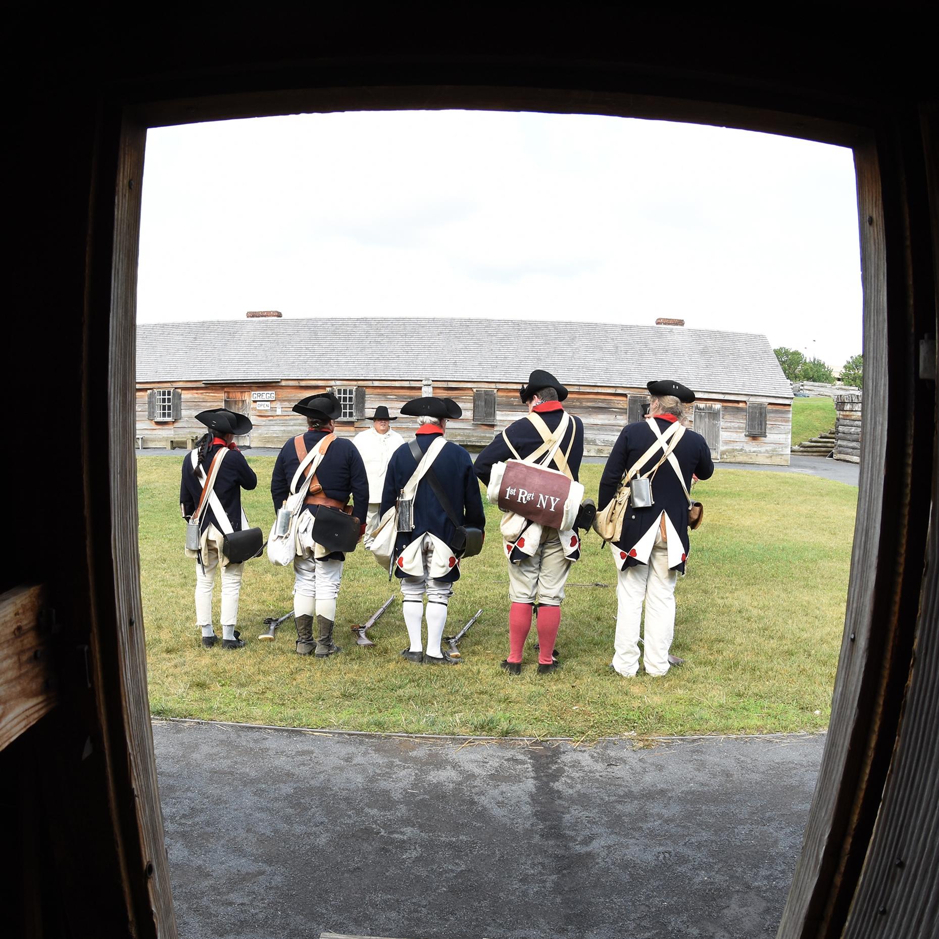 Out of a doorway, you can see several Continental soldiers standing in a line, facing away from you.