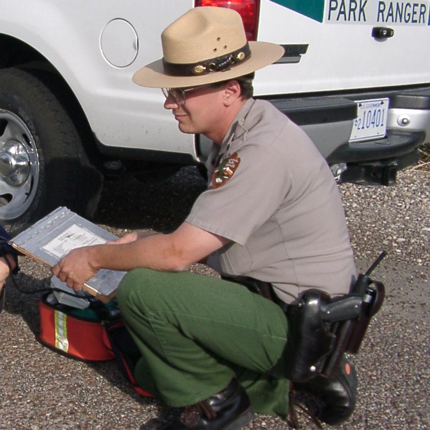 Park Ranger kneels next to a vehicle