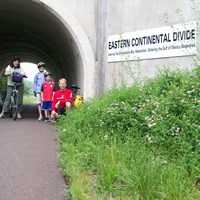 family of bicyclists at the Eastern Continental Divide on the Great Allegheny Passage rail-trail
