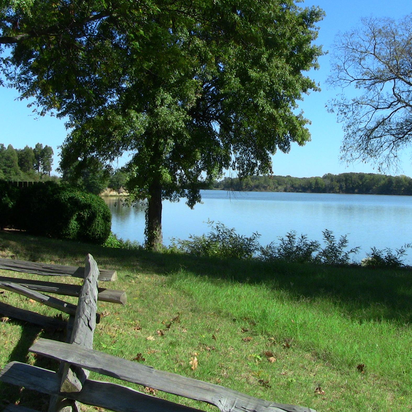 view of wide, tidal creek with trees and split rail fence in foreground