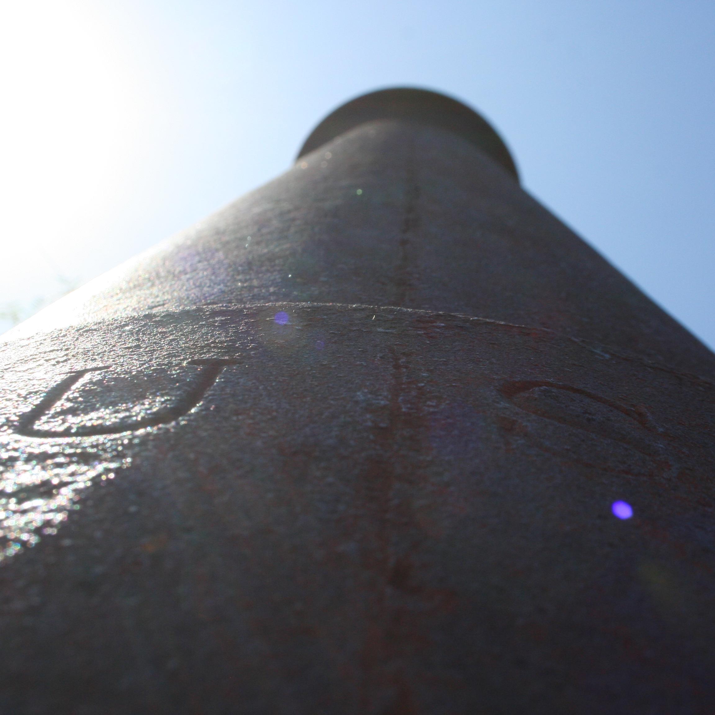 Looking up towards the sky along the barrel of a replica cannon.