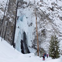 Skiers make their way to the bottom of frozen Fairy Falls in winter.