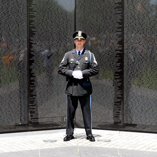 US Park Police Officer standing in front of the Vietnam Veterans Memorial.