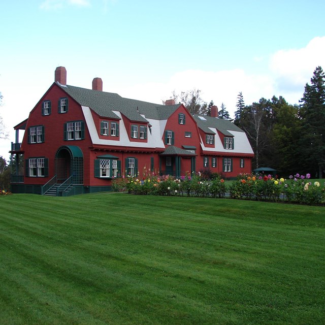 Red cottage on wide grassy lawn