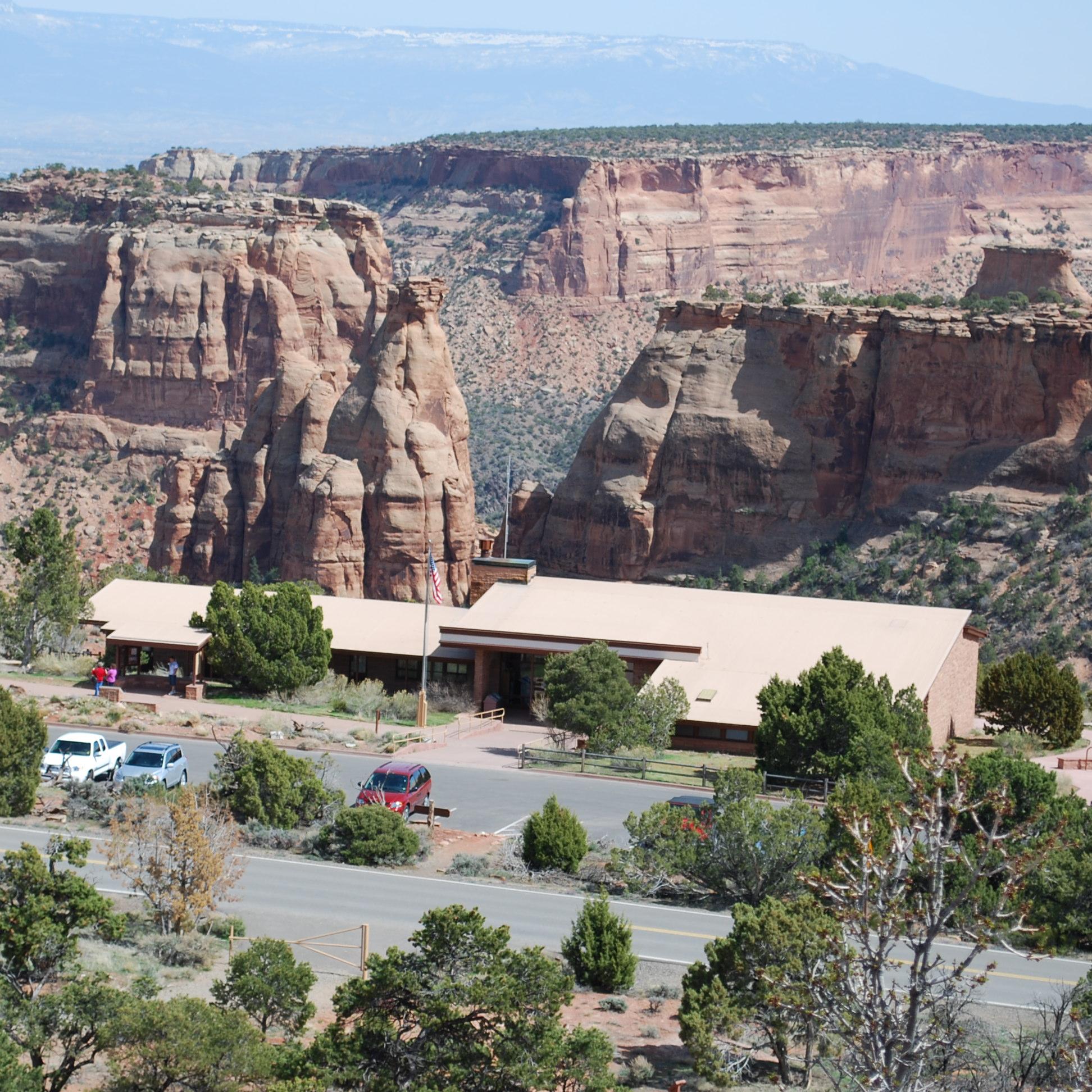 low, flat brown building surrounded by trees and parking lot, backdrop of steep canyon walls