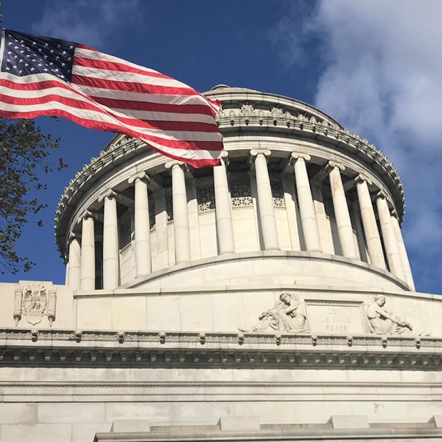 U.S. flag flying near a classical-style temple with prominent columns 