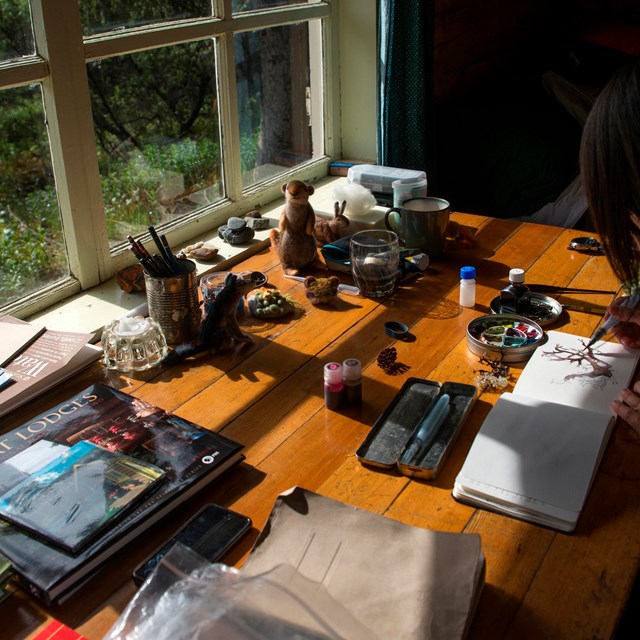 A woman painting with watercolors at a desk