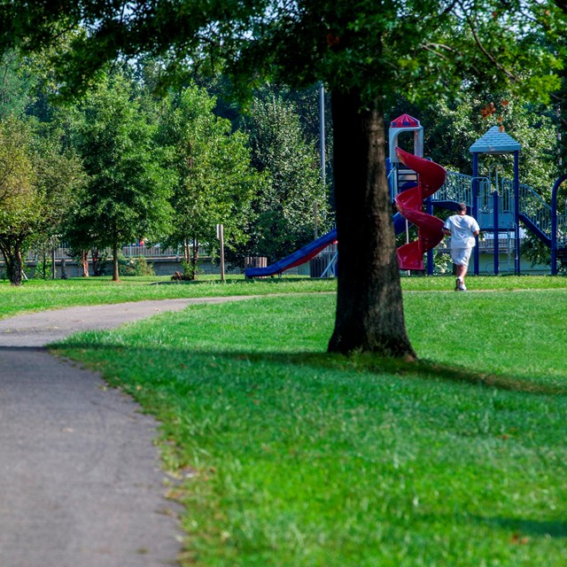 A man runs on a trail going through the park.