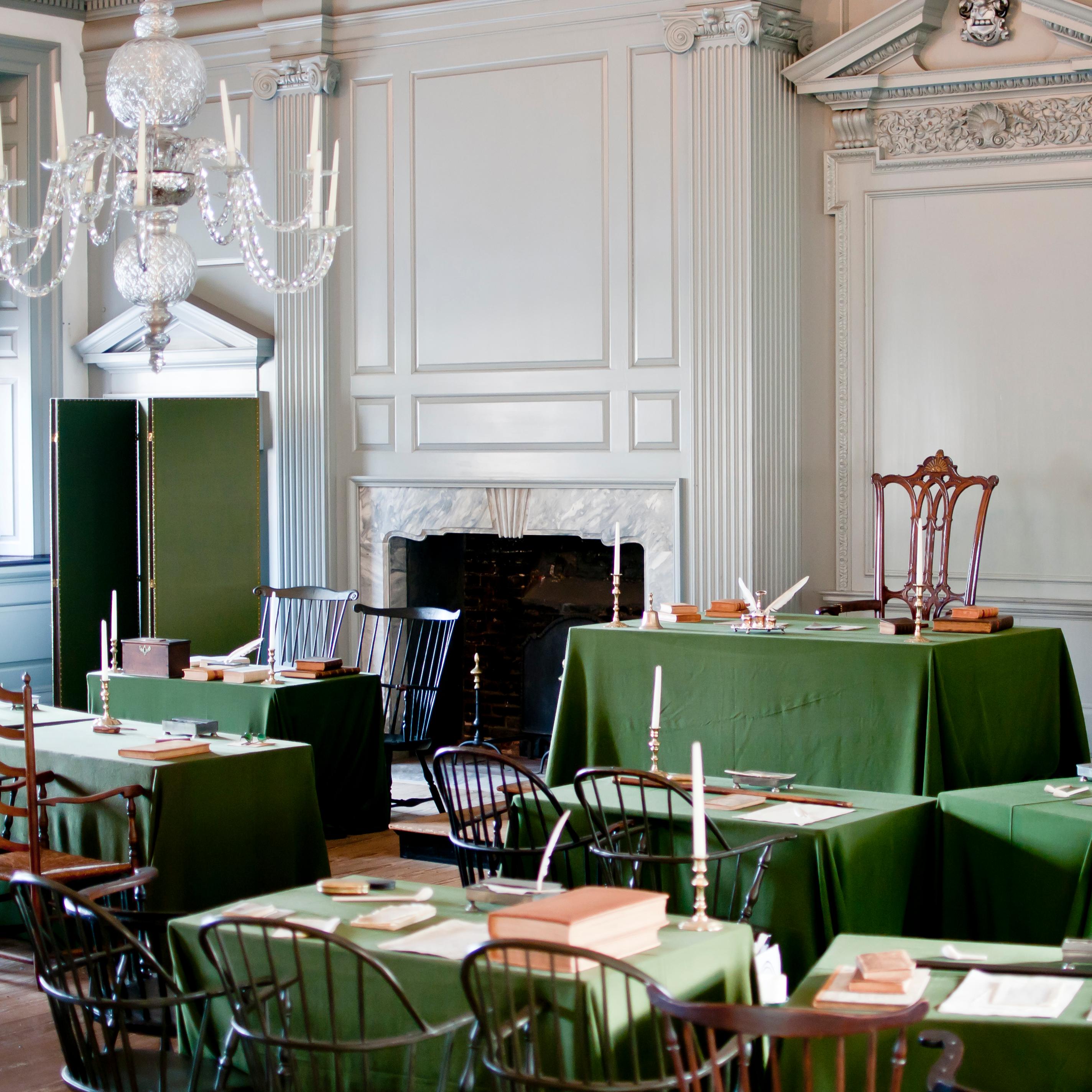 Color photo of the Assembly Room, showing chairs grouped around tables covered with green cloth.