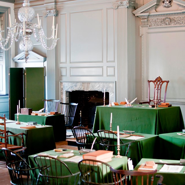 Color photo of the Assembly Room, showing chairs grouped around tables covered with green cloth.