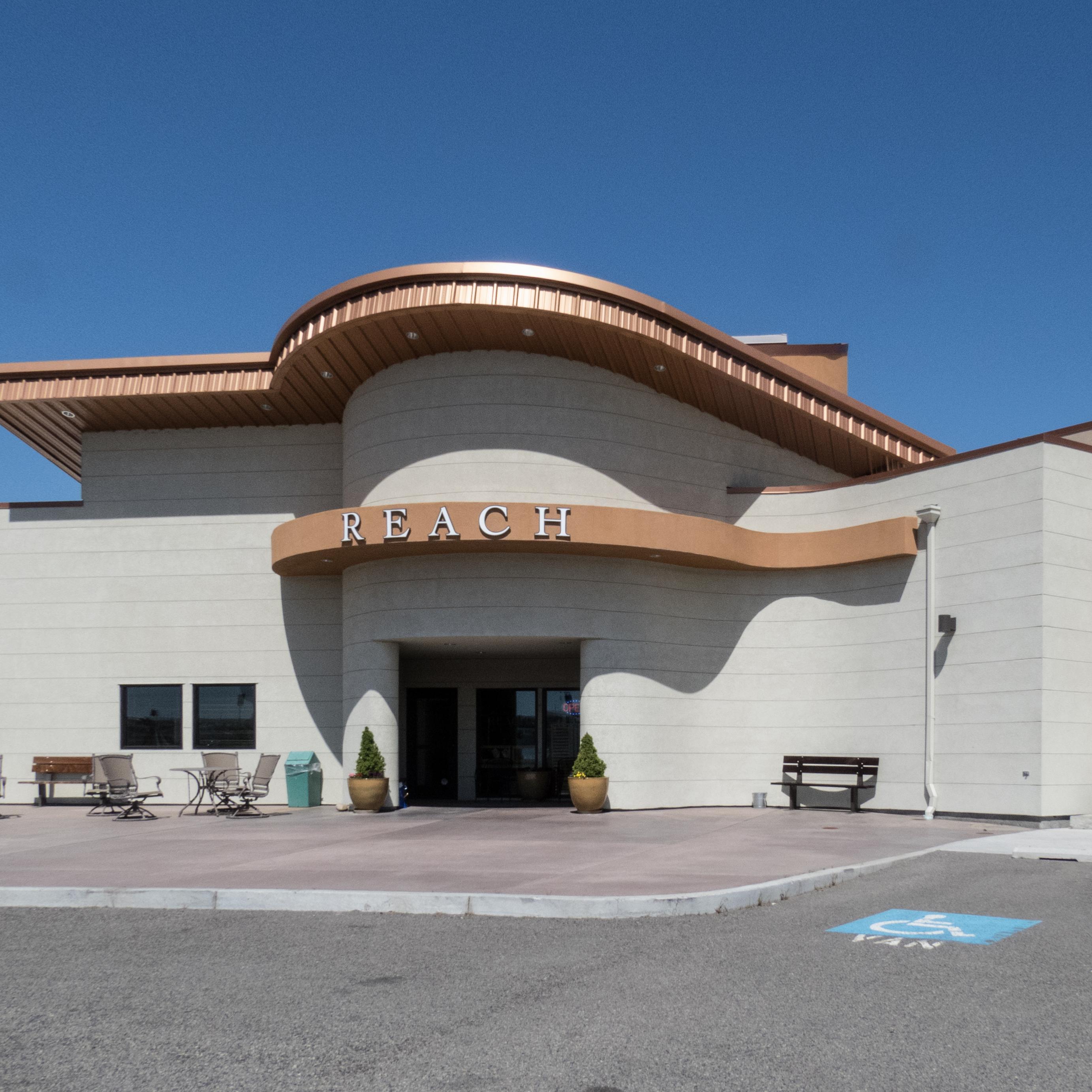 Color photograph of a cement brick building with an ornate copper roof. A sign reads 