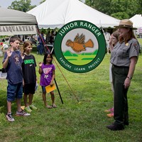 Children stand at attention with hands raised to become park junior rangers