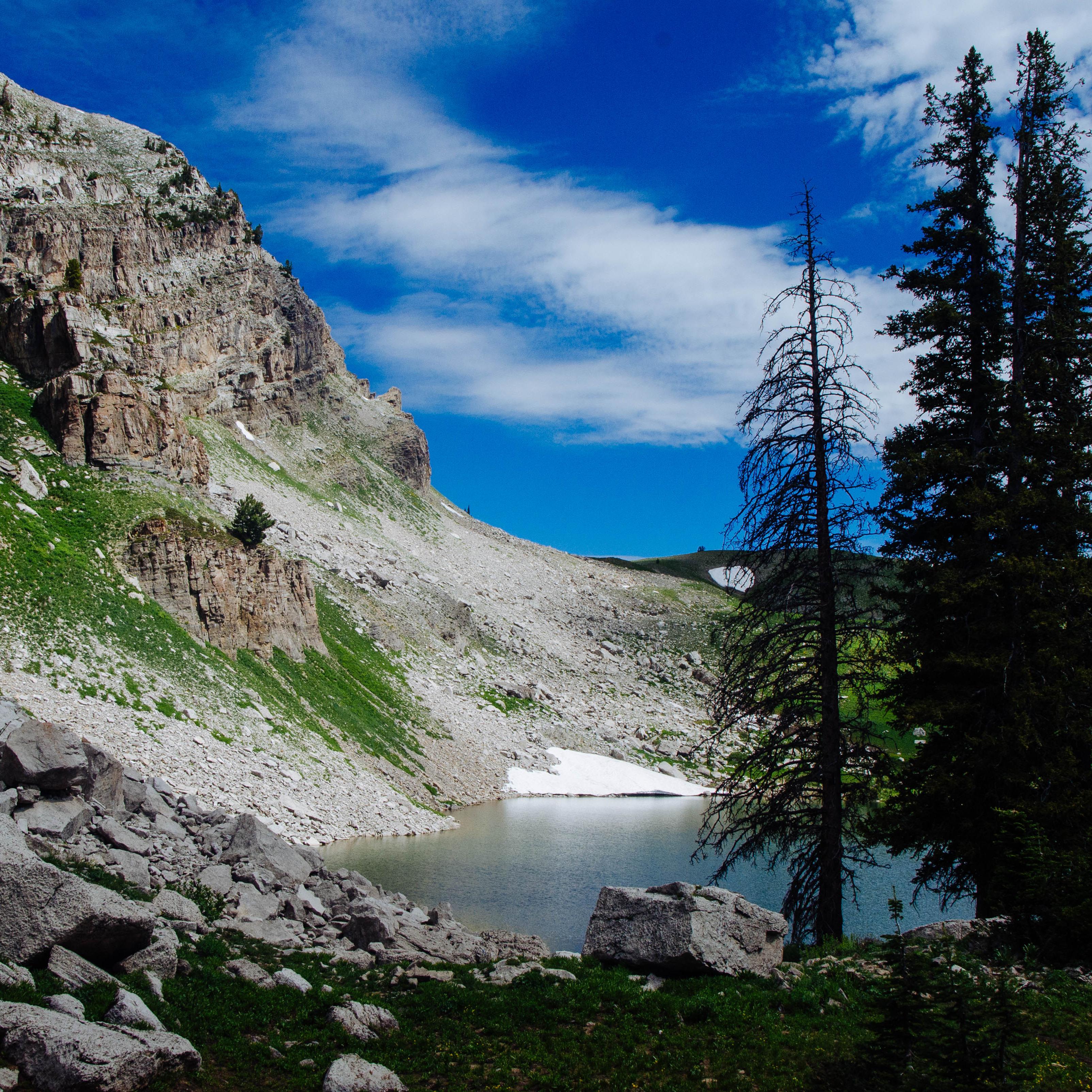 An alpine lake sits at the base of a rocky cliff.