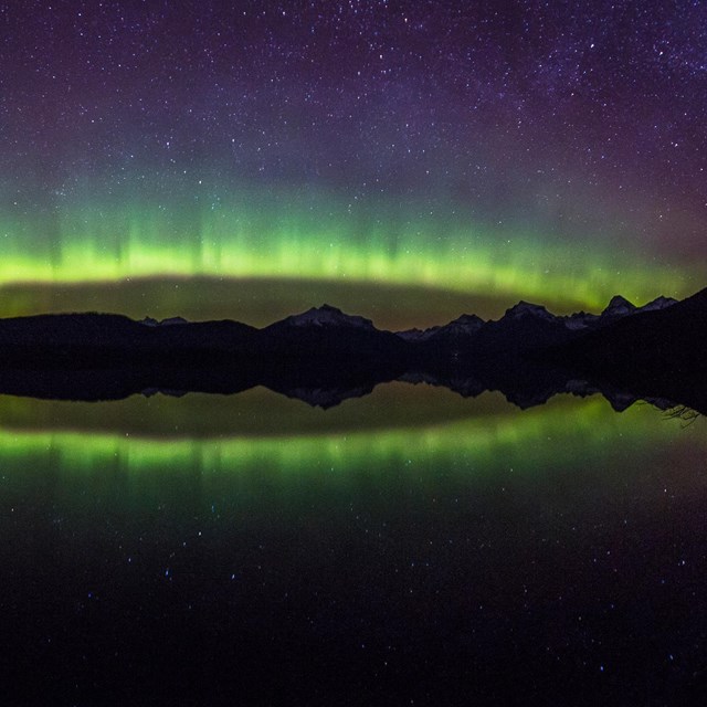 The brilliant colors of the aurora borealis arc over a mountain lake
