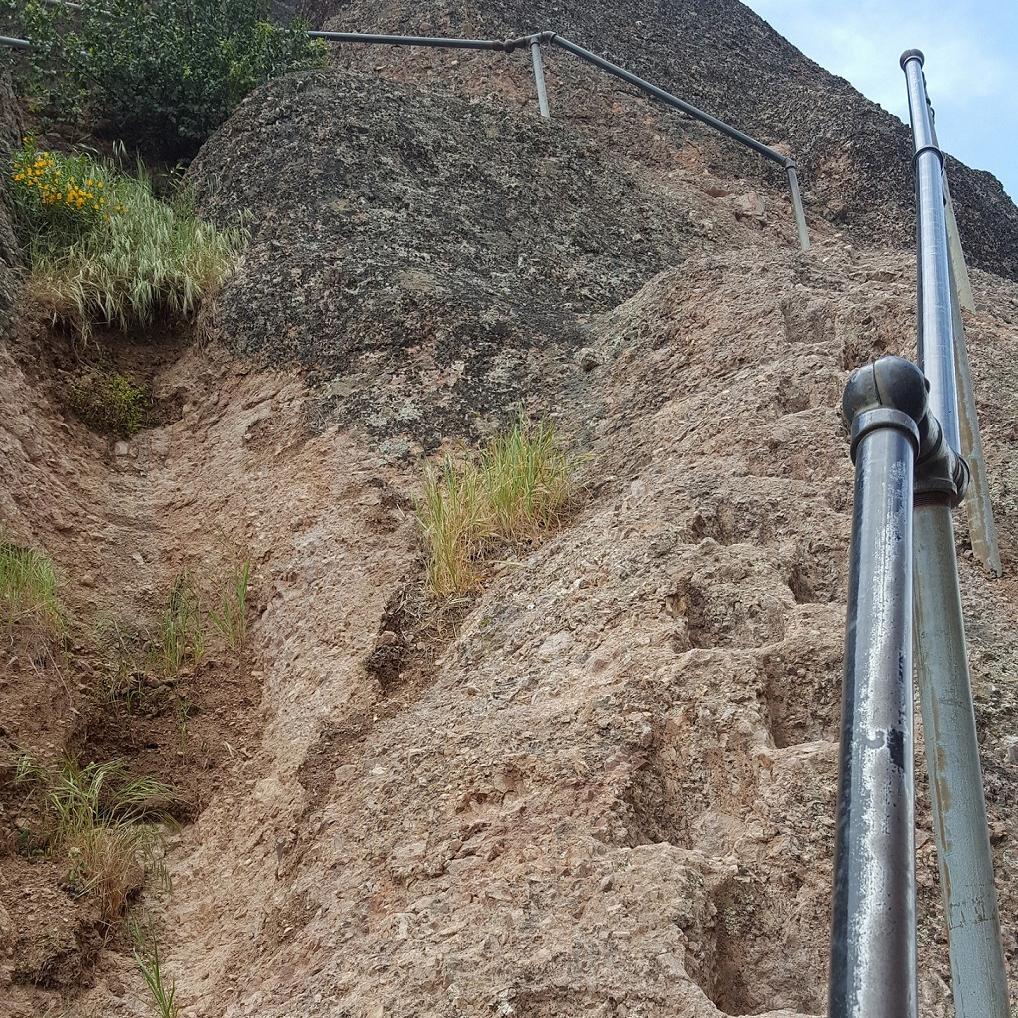 Handrail and series of foot notches carved into steep rock.