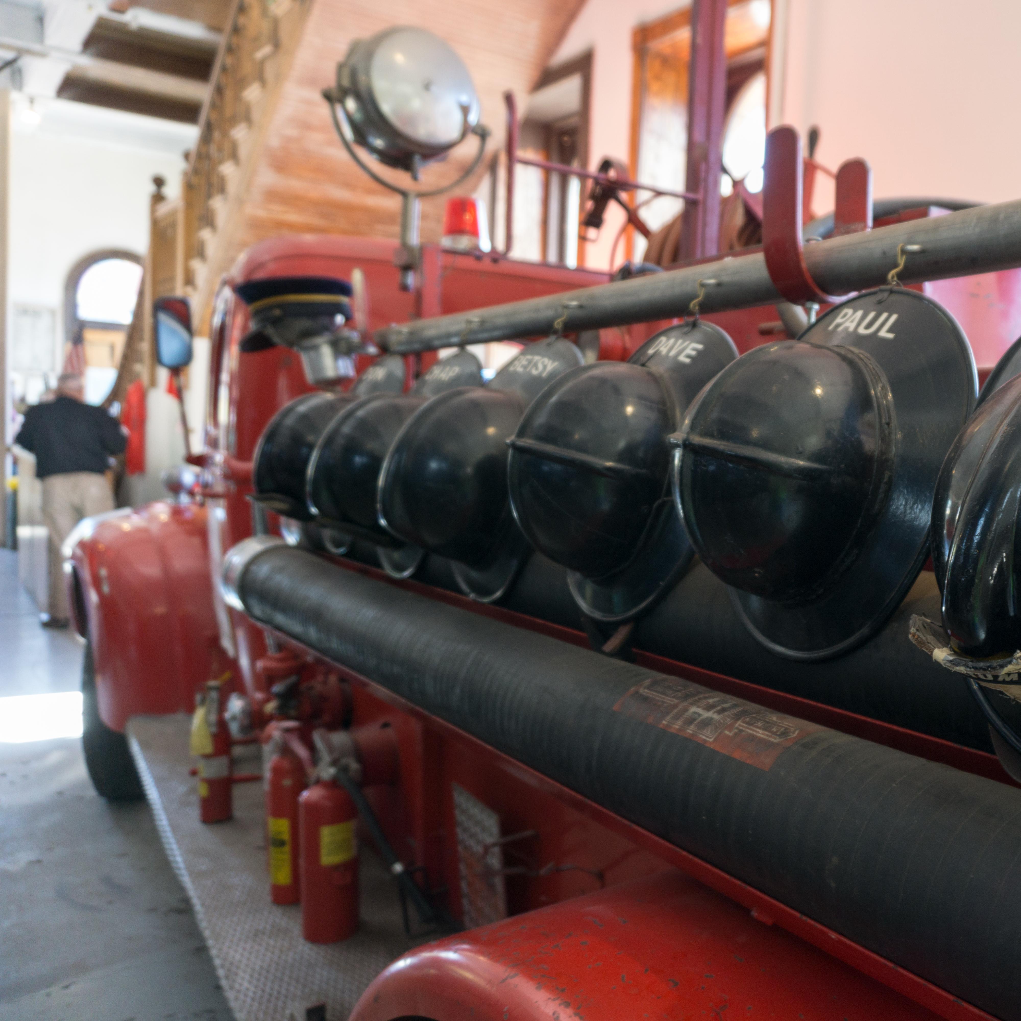 a historic fire truck with helmets mounted on the side