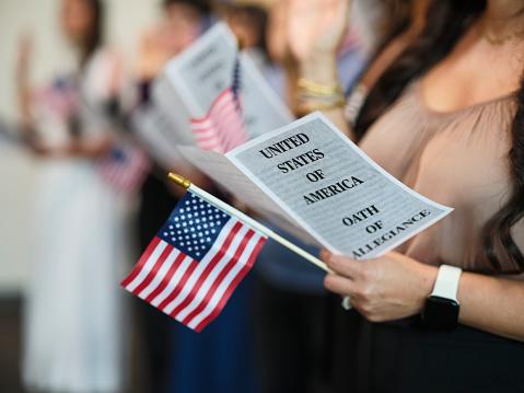 Women holding a small American flag taking the oath.