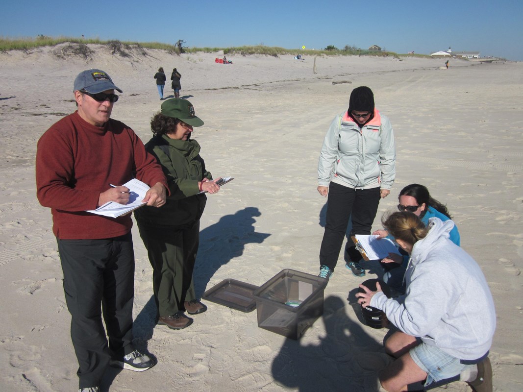 A group of teachers dressed for the cold hold science instruments and record data with a park ranger